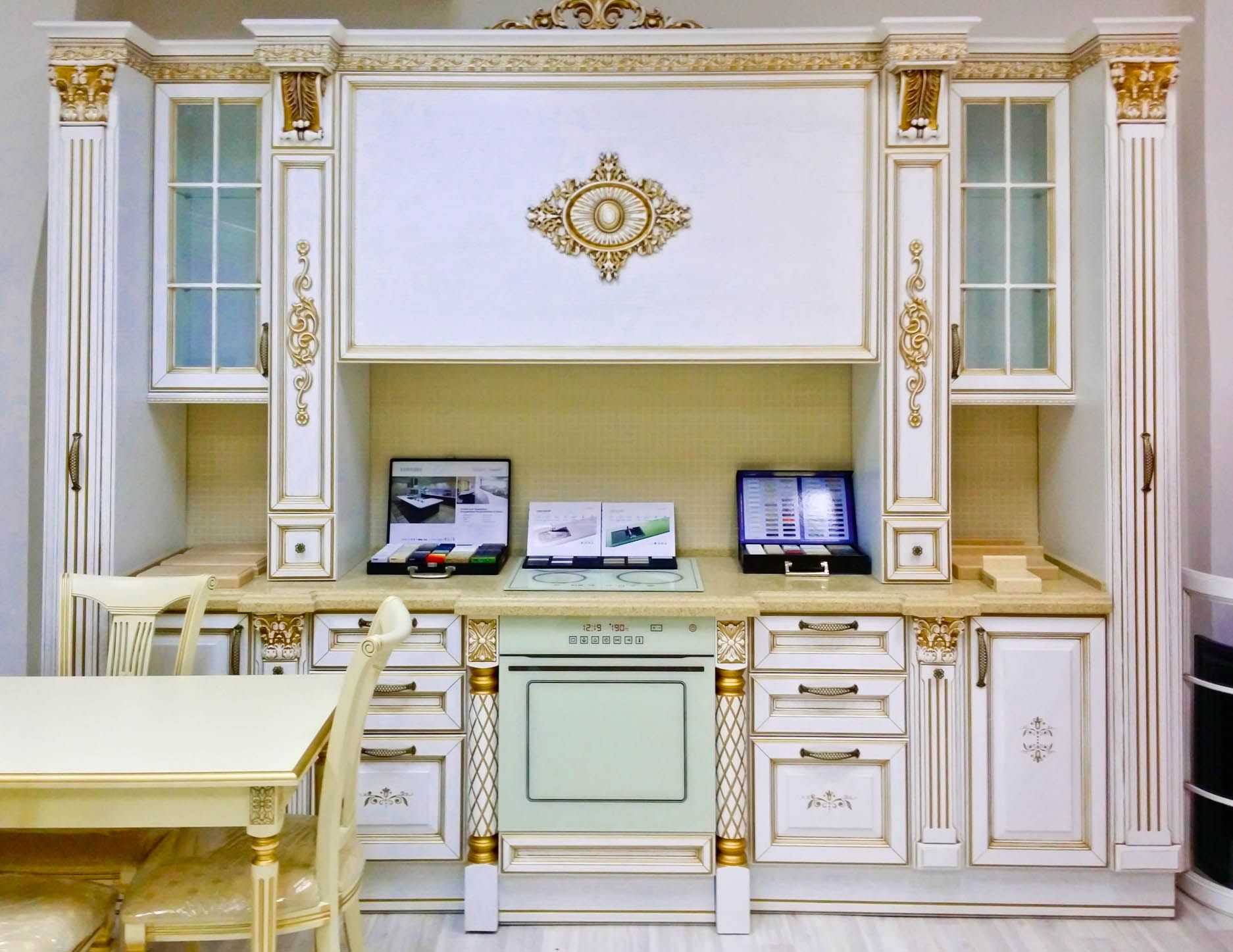 Кухня Доротея в классическом белом стиле с золотым обрамлением декоративными элементами на фасаде 